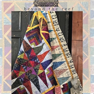 May include: A colorful quilt with a geometric pattern, featuring a variety of colors including red, purple, yellow, and blue. The quilt is folded and draped over a chair. The text "beyond the reef" and "palm canyon" is visible on the image.