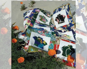 Pode incluir: Um cobertor com tema havaiano com um patchwork de estampas florais e tropicais coloridas. O cobertor está dobrado e colocado em uma praia de areia com flores laranja em primeiro plano. O texto "aloha shirts" e "@quiltedorigami" é visível na parte inferior da imagem.