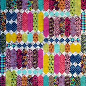 May include: A colorful quilt with a geometric pattern. Vertical columns of various patterned fabrics in shades of pink, yellow, teal, purple, and green are arranged in a repeating design. The quilt features floral, geometric, and plaid patterns.