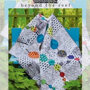 May include: A white quilt with a black and white geometric pattern and colorful circles connected by lines. The quilt is folded and draped over a blue bench. The text "string o' pearls" is at the bottom of the image.