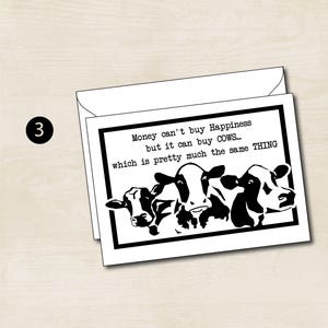 May include: A black and white greeting card with a humorous quote about cows and happiness. The text reads: "Money can't buy Happiness but it can buy COWS... which is pretty much the same THING". The card features a black and white illustration of three cows.