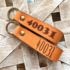 May include: Two brown leather keychains with silver key rings. The keychains are engraved with the number "40031".