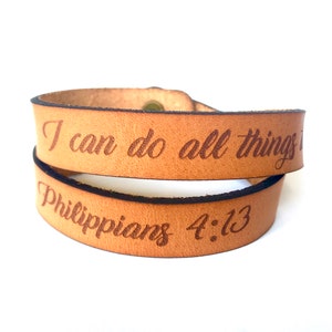 May include: A brown leather wrap bracelet with the text "I can do all things through Christ who strengthens me" and "Philippians 4:13" engraved on it.