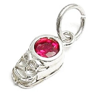 May include: Silver charm with a red gemstone set in a skull design. The charm has a loop for attaching to a bracelet or necklace.