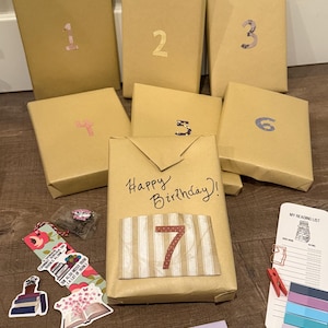 May include: A collection of wrapped books with numbers 1-7, perfect for a birthday gift. The central package reads "Happy Birthday!" and includes a decorative number 7. Also includes a bookmark, stickers, and a reading list.