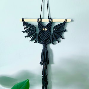 May include: Black macrame bat wall hanging with wooden dowel and black bead eyes.