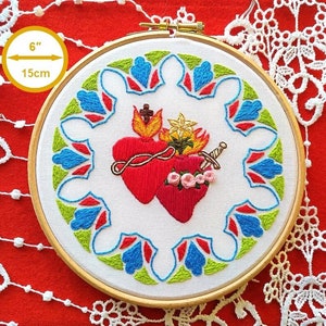 May include: Embroidered hoop art featuring two red hearts with a crown of thorns, a sword, and flames. The hearts are surrounded by a colorful geometric pattern. The hoop is 6 inches (15 cm) in diameter.