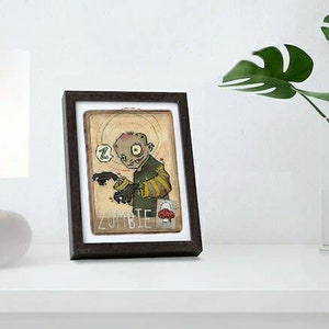 Pode incluir: Uma ilustração emoldurada de um zumbi de desenho animado com pele verde e uma camisa listrada amarela e marrom. O zumbi está segurando um pequeno objeto redondo em sua mão. A ilustração está em um fundo bege com a palavra "ZOMBIE" impressa em preto na parte inferior.