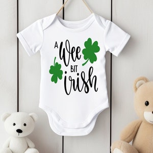 Può includere: Un body bianco per neonato con un trifoglio verde e il testo "A wee bit irish" in nero.