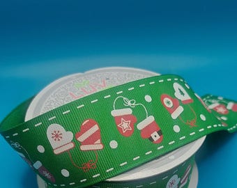 May include: A roll of green ribbon with a white dashed line and white polka dots. The ribbon has a repeating pattern of red and white mittens, red and white hats, and snowflakes.
