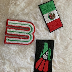 Könnte beinhalten: Drei gestickte Aufnäher mit mexikanischen Motiven. Einer ist ein stilisiertes "B" in Rot, Weiß und Grün. Ein weiterer ist die mexikanische Flagge. Der dritte Aufnäher zeigt ein stilisiertes Adlerdesign in Rot, Grün und Weiß auf schwarzem Hintergrund.