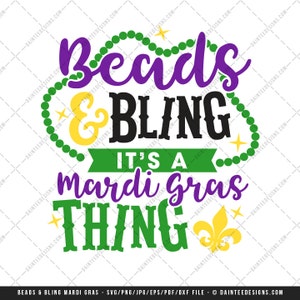May include: A graphic design with the text "Beads & Bling, It's a Mardi Gras Thing." The design features purple, green, yellow, and black colors, with a fleur-de-lis symbol. The words are surrounded by decorative elements.