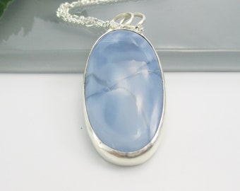 May include: A silver chain necklace with a light blue oval pendant featuring a swirling pattern. The pendant is set in a silver bezel.