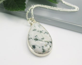 May include: A silver chain necklace with a teardrop-shaped pendant featuring a white and green moss agate stone.