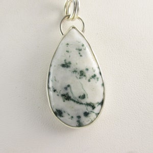 May include: A silver pendant with a teardrop-shaped green and white agate stone.