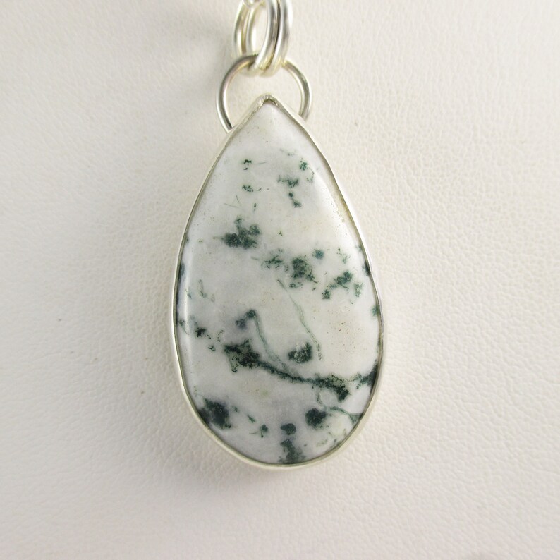 May include: A silver pendant with a teardrop-shaped green and white agate stone.
