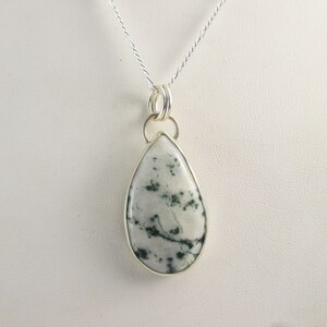 May include: A silver chain necklace with a teardrop-shaped pendant featuring a white and green agate stone.
