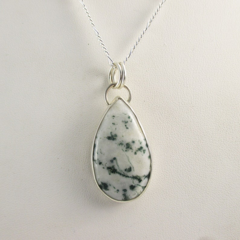 May include: A silver chain necklace with a teardrop-shaped pendant featuring a white and green agate stone.