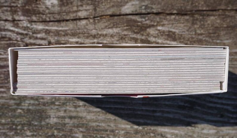 May include: A close-up view of the top of a stack of white cards with a red border. The cards are stacked neatly and are all the same size.
