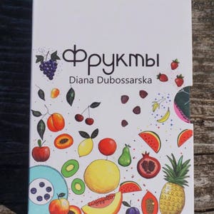 May include: A white box with a colorful illustration of various fruits, including grapes, cherries, peaches, lemons, watermelon, kiwi, pineapple, and papaya. The text "Фрукты" and "Diana Dubossarska" is printed on the box.