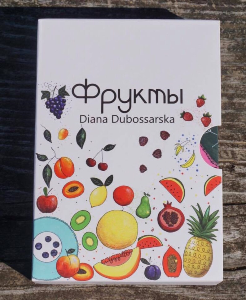 May include: A white box with a colorful illustration of various fruits, including grapes, cherries, peaches, lemons, watermelon, kiwi, pineapple, and papaya. The text "Фрукты" and "Diana Dubossarska" is printed on the box.