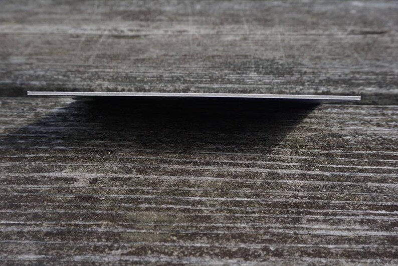 May include: A close-up of a blank, white card with rounded corners. The card is lying flat on a wooden surface.