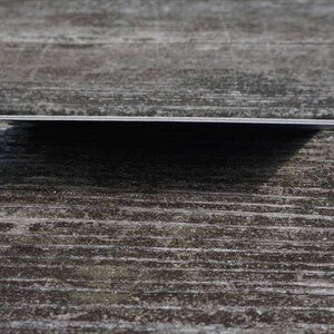 May include: A close-up of a blank, white card with rounded corners. The card is lying flat on a wooden surface.