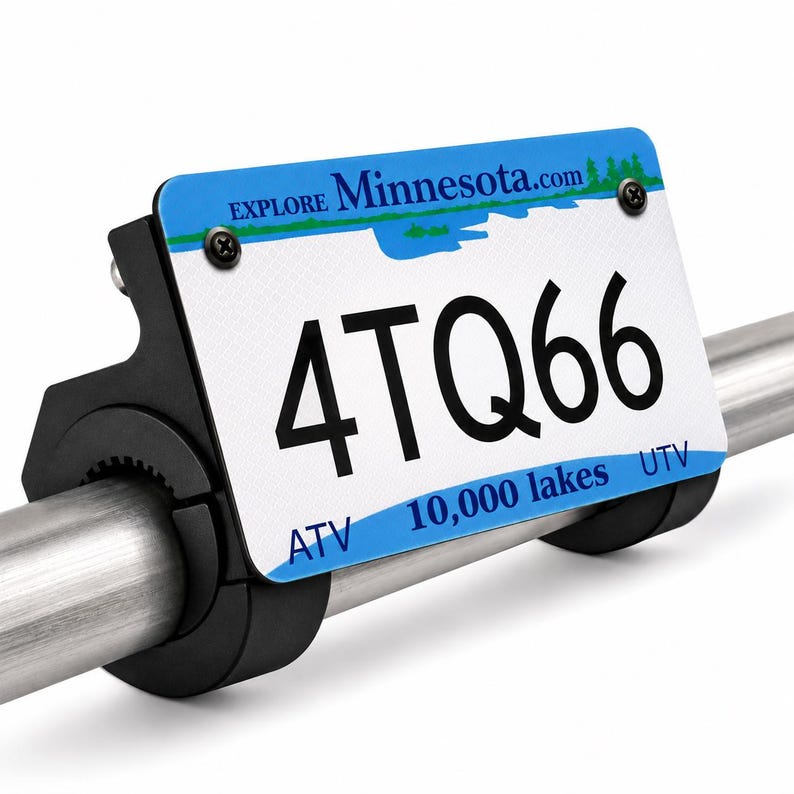Puede incluir: Una placa de matr&iacute;cula blanca y azul de Minnesota con el texto EXPLORE Minnesota.com, 4TQ66, 10,000 lakes, ATV y UTV. La placa est&aacute; sujeta a una barra de metal plateado mediante un soporte de montaje de pl&aacute;stico negro con dos tornillos.