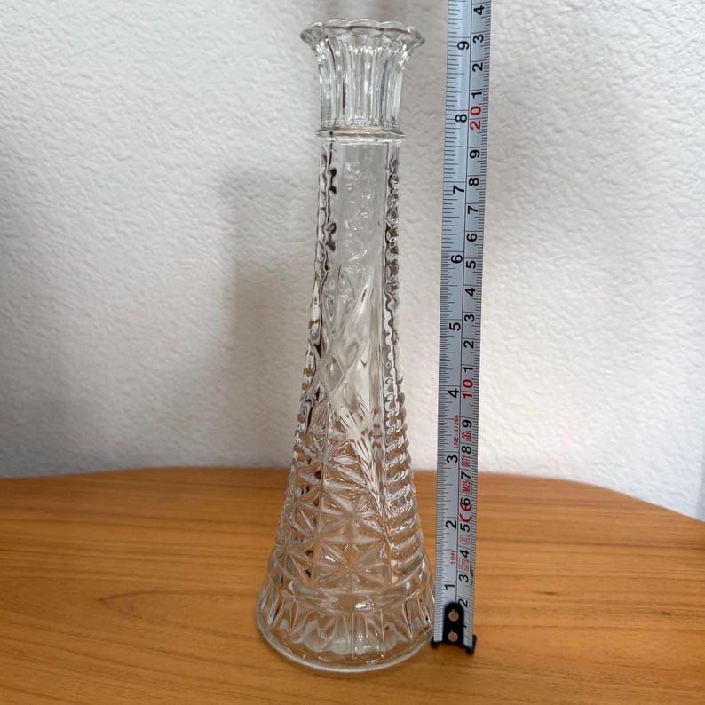 Pu&ograve; includere: Un vaso di vetro trasparente con un design strutturato a forma di diamante. Il vaso &egrave; alto e sottile, con una base svasata e una parte superiore decorativa. Il vaso misura circa 23 cm di altezza.
