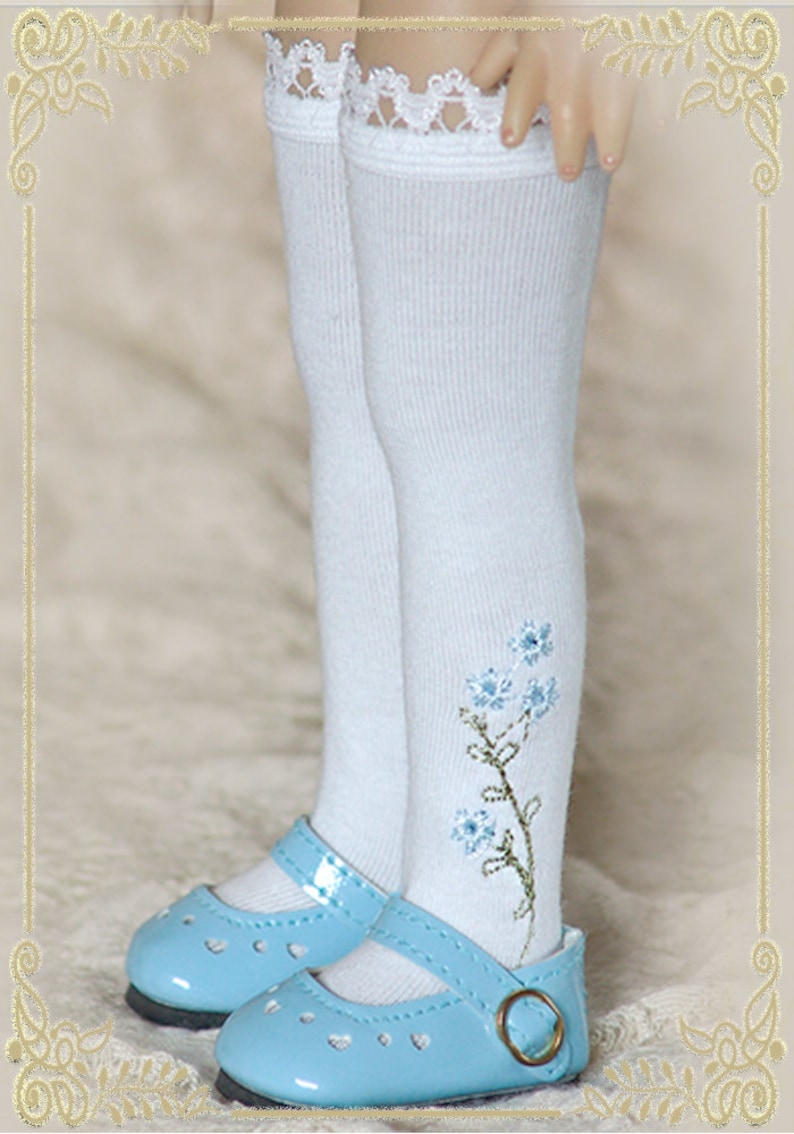 May include: White knee-high socks with a lace trim and blue embroidered flowers. The socks are paired with light blue patent leather shoes with a buckle.