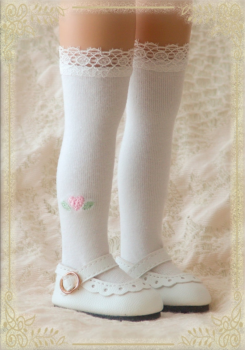 May include: White knee-high socks with a lace trim and a pink heart embroidered on one sock. The socks are paired with white shoes with a buckle.