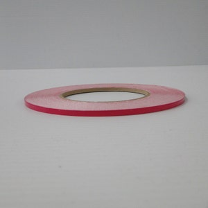 May include: A roll of pink tape with a brown paper core.