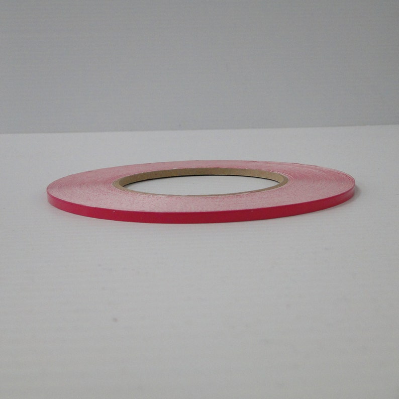 May include: A roll of pink tape with a brown paper core.