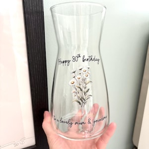 Puede incluir: Jarrón de vidrio transparente con un diseño floral y el texto "Happy 80th birthday to a lovely mum & grandma".