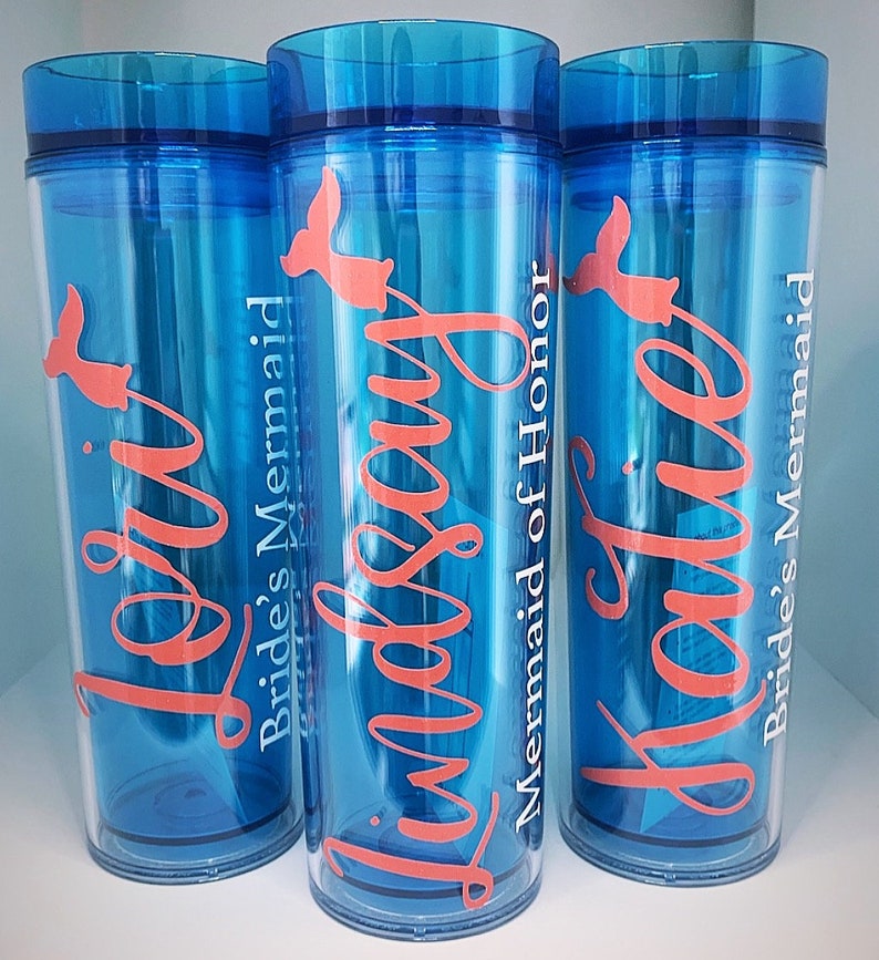 Peut inclure: Trois gobelets bleus avec du texte blanc et un motif de sir&egrave;ne rose. Les gobelets disent "Bride's Mermaid", "Maid of Honor" et "Bride's Mermaid".