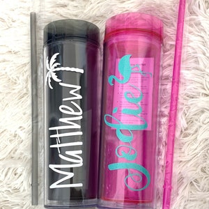 Peut inclure: Deux gobelets en plastique transparent avec couvercles et pailles. Un gobelet est noir avec un palmier blanc et le nom "Matthew" en lettres blanches. L'autre gobelet est rose avec un flamant rose turquoise et le nom "Jodi" en lettres turquoise.