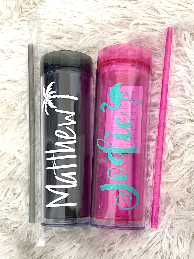 Peut inclure: Deux gobelets en plastique transparent avec couvercles et pailles. Un gobelet est noir avec un palmier blanc et le nom "Matthew" en lettres blanches. L'autre gobelet est rose avec un flamant rose turquoise et le nom "Jodi" en lettres turquoise.