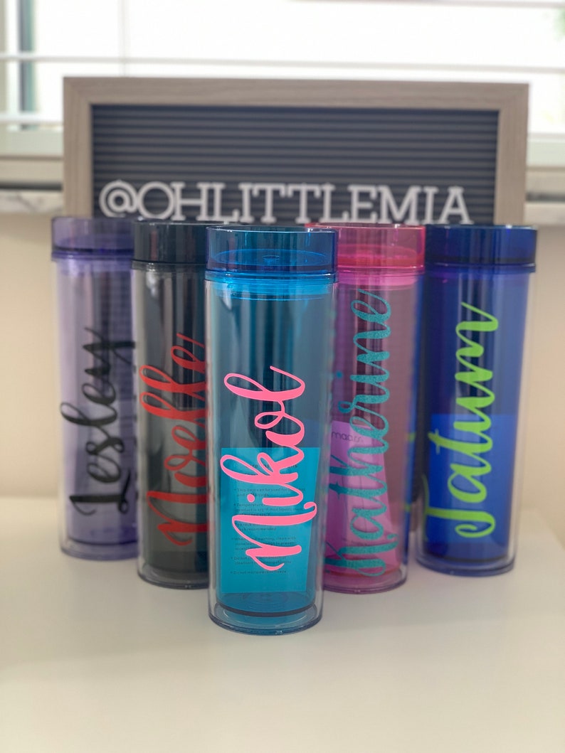 Peut inclure: Cinq gobelets en plastique transparent personnalis&eacute;s avec des couvercles de couleurs diff&eacute;rentes et des noms &eacute;crits dessus en diff&eacute;rentes couleurs. Les noms sont "Lesley", "Ashley", "Nikol", "Brittany" et "Autumn".