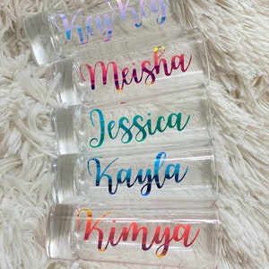 Puede incluir: Cinco vasos de chupito transparentes con nombres coloridos e iridiscentes. Los nombres son: Key Key, Meisha, Jessica, Kayla y Kimya.