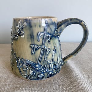 Caneca de cerâmica artesanal com tema de naufrágio, xícara de café com arte oceânica e cracas.