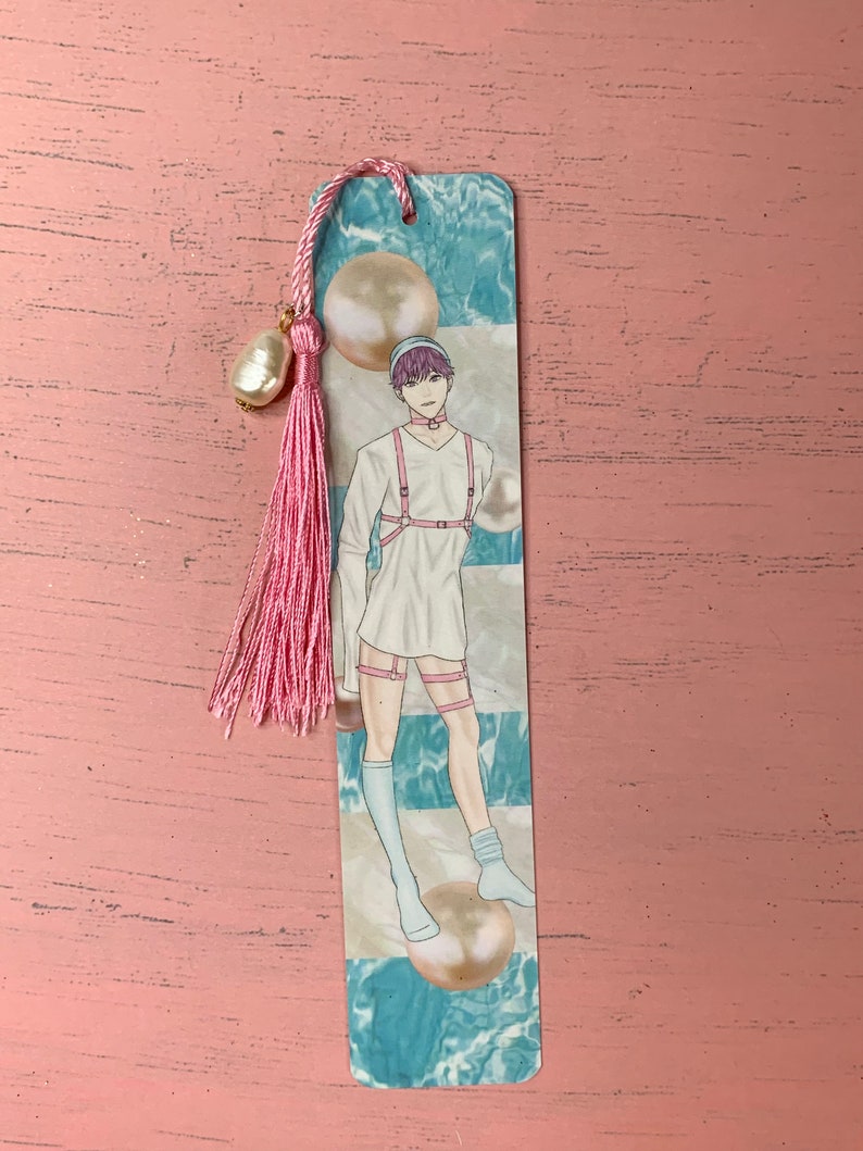 K&ouml;nnte beinhalten: Ein Lesezeichen mit einer Cartoon-Illustration einer Person mit rosa Haaren, die ein wei&szlig;es Outfit mit einem rosa Gurtzeug und wei&szlig;en Socken tr&auml;gt. Der Hintergrund ist ein blaues und wei&szlig;es abstraktes Design mit gro&szlig;en perlmuttartigen Kugeln.