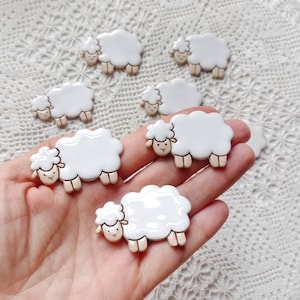 May include: A collection of white ceramic sheep figurines. The sheep are all different sizes and have a simple, minimalist design.