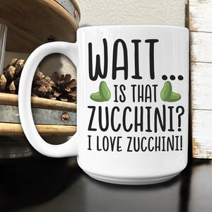 May include: White ceramic coffee mug with a black and green graphic that says "WAIT... IS THAT ZUCCHINI? I LOVE ZUCCHINI!"