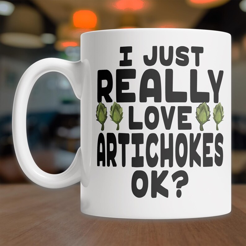 May include: White ceramic coffee mug with a black graphic that says "I just really love artichokes ok?" with green artichoke illustrations.