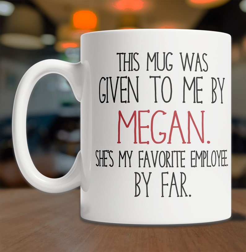 May include: White ceramic mug with black text that reads "This mug was given to me by Megan. She's my favorite employee by far."