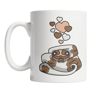May include: White ceramic mug with a brown and white snake design. The snake is curled up with its head peeking out. There are pink and white hearts floating above the snake.