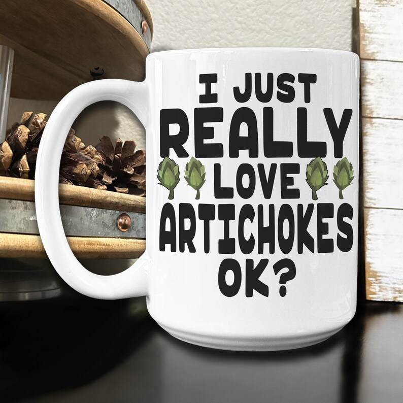 May include: White ceramic coffee mug with a black graphic that reads "I just really love artichokes ok?" with three green artichoke illustrations.