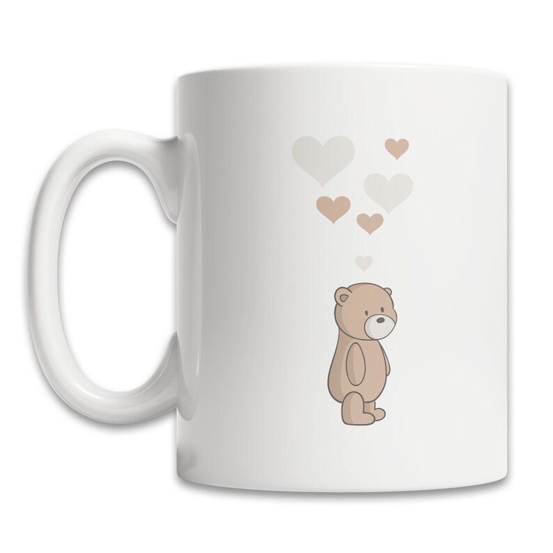 May include: White ceramic mug with a brown teddy bear illustration and a cluster of light brown and gray hearts above the bear.