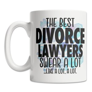 May include: White ceramic mug with the text "THE BEST DIVORCE LAWYERS SWEAR A LOT...LIKE A LOT, A LOT." in black lettering. The design includes a watercolor-style blue and purple background.