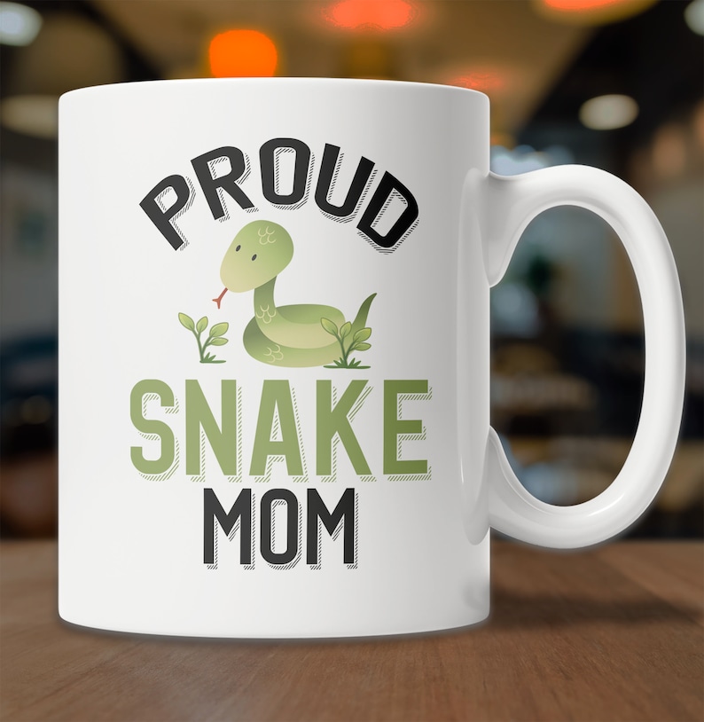 May include: White ceramic coffee mug with a green snake illustration and the text "PROUD SNAKE MOM" in black.